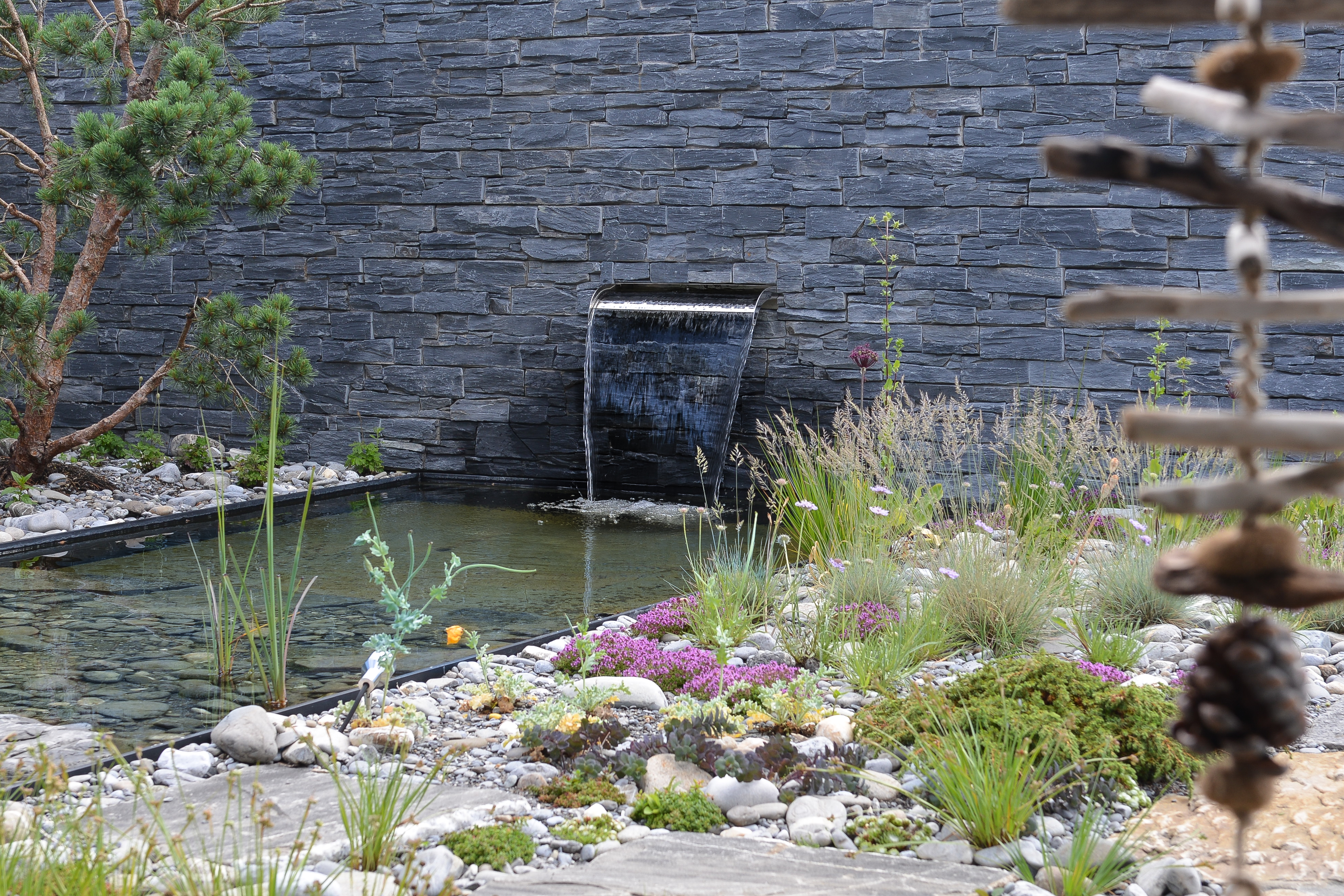 Steingartenbepflanzung auf Terrasse mit kleinem Wasserfall