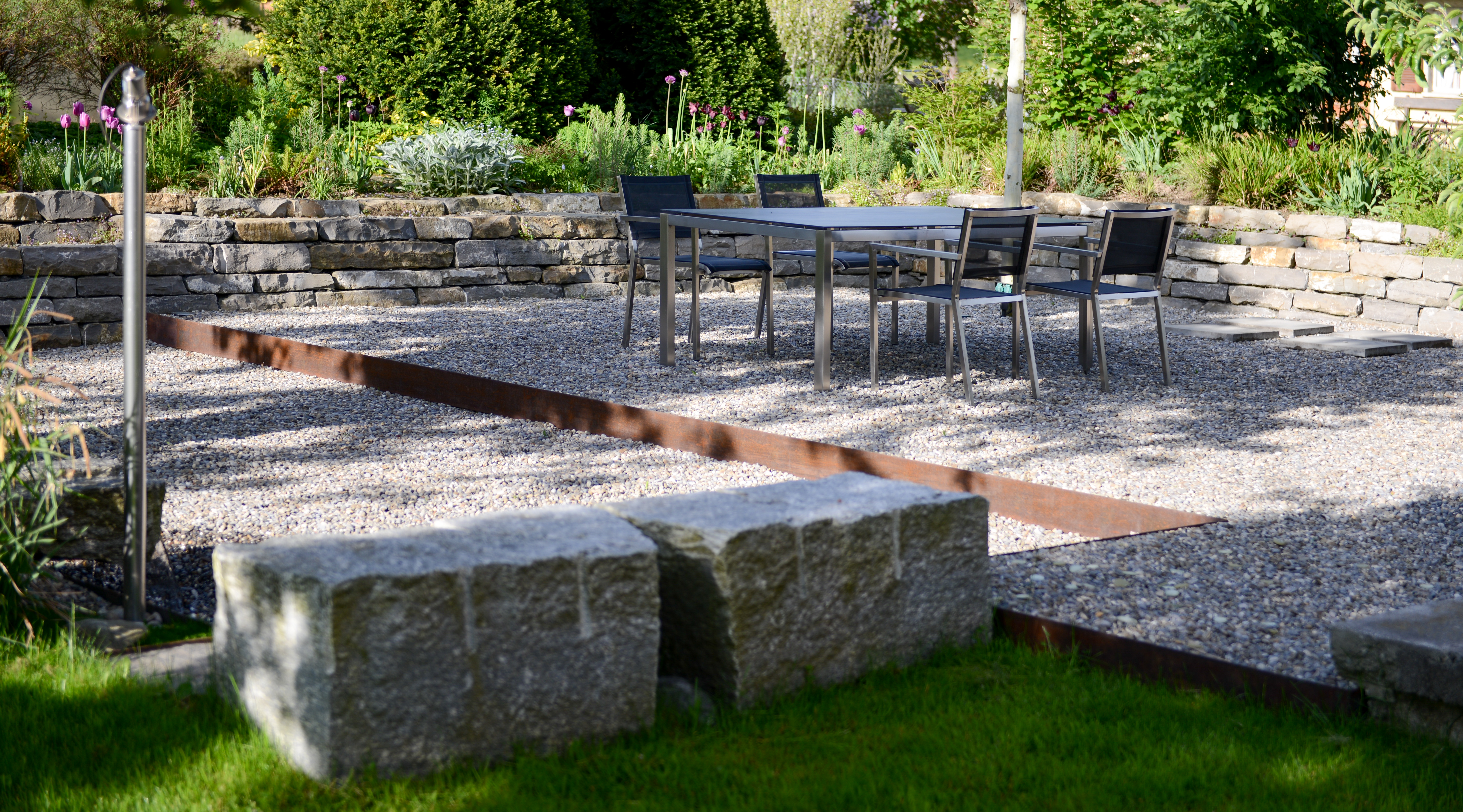 Sitzsteine und gerundete Sitzmauer ergänzen die Gartenmöblierung