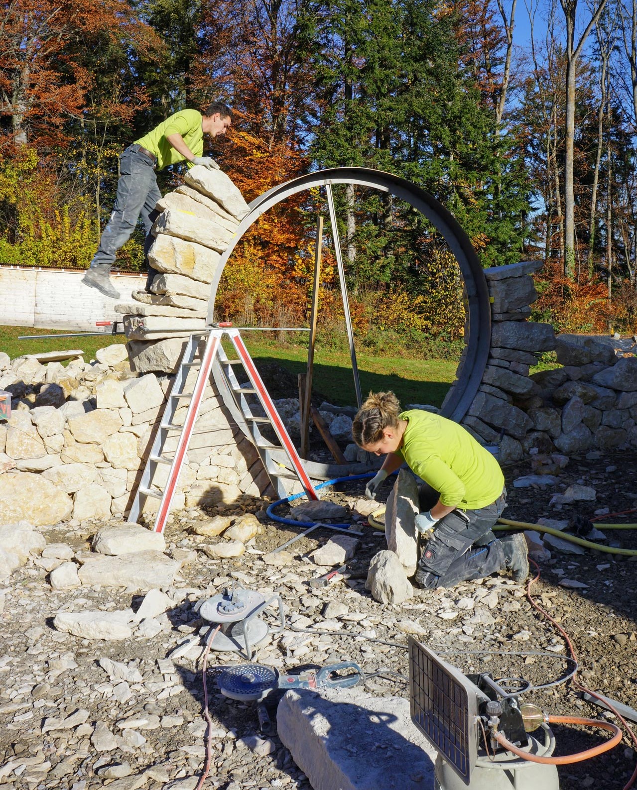 Mitarbeiter von Knechtgarten bauen ein rundes Tor aus Naturstein