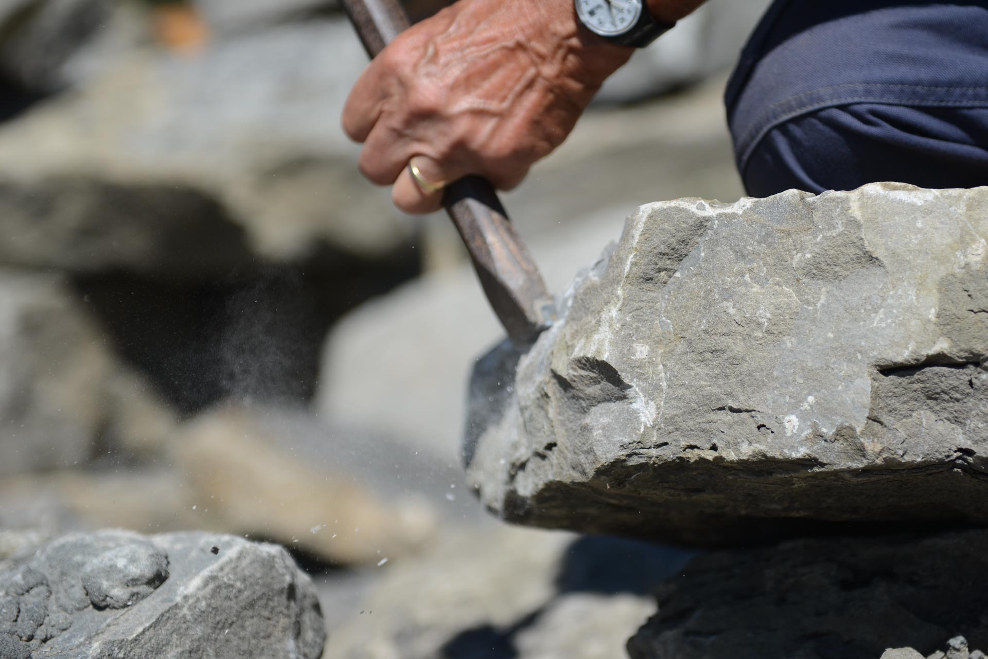 Ein Kalkstein wird mit Hammer und Meissel bearbeitet.